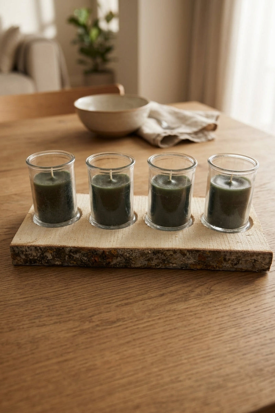 Holzplatte mit vier Glaswindlichtern in Grau als Tischdekoration